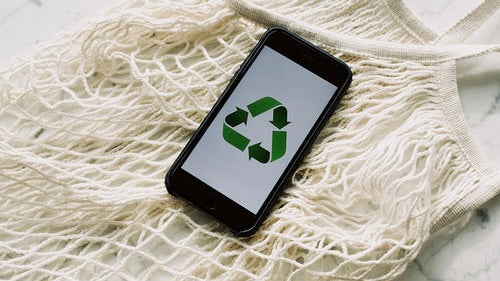 How to spot false sustainability claims: smartphone displaying a recycling symbol on a textured background.